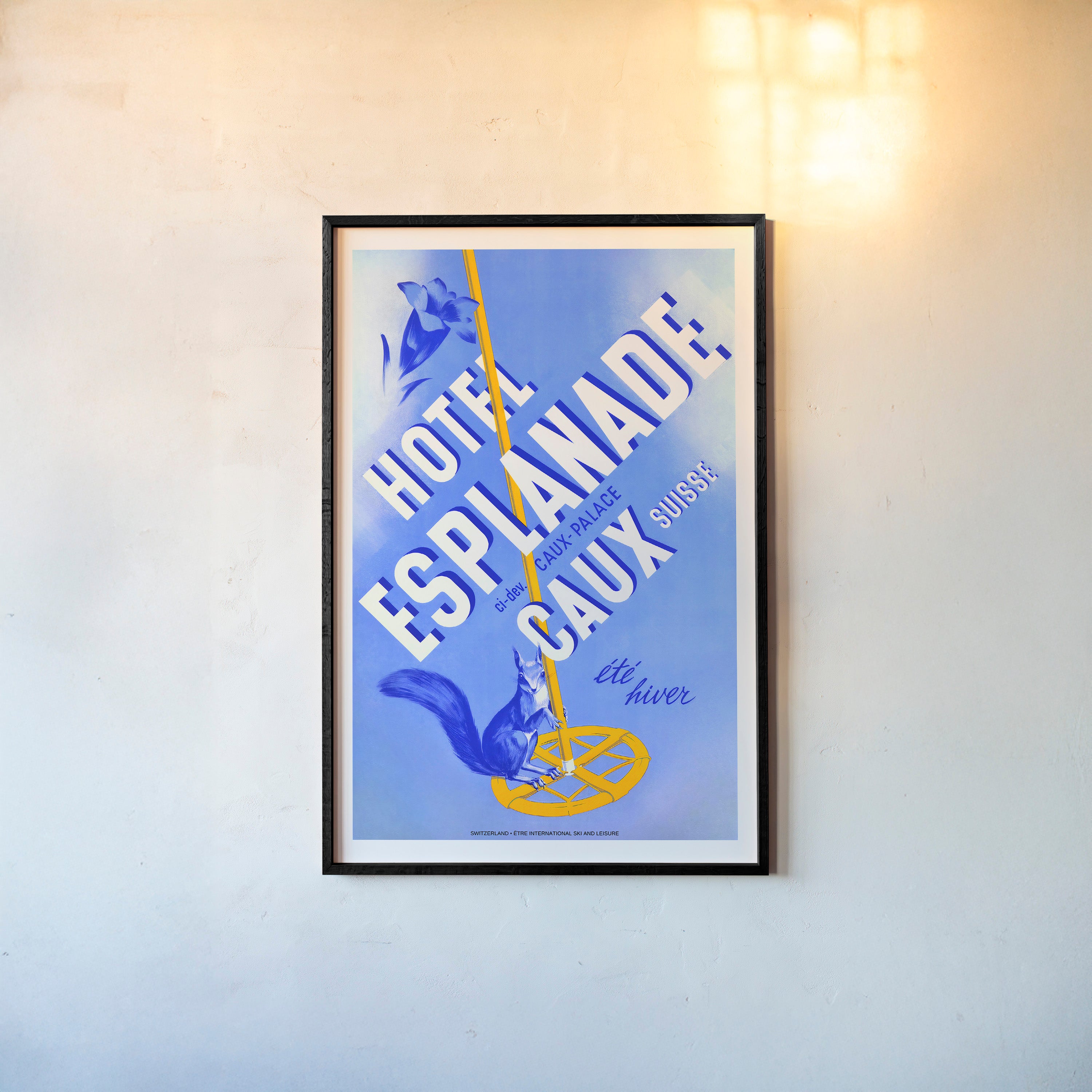 Framed poster of "Hotel Esplanade Caux" with a blue background hanging on a light backdrop
