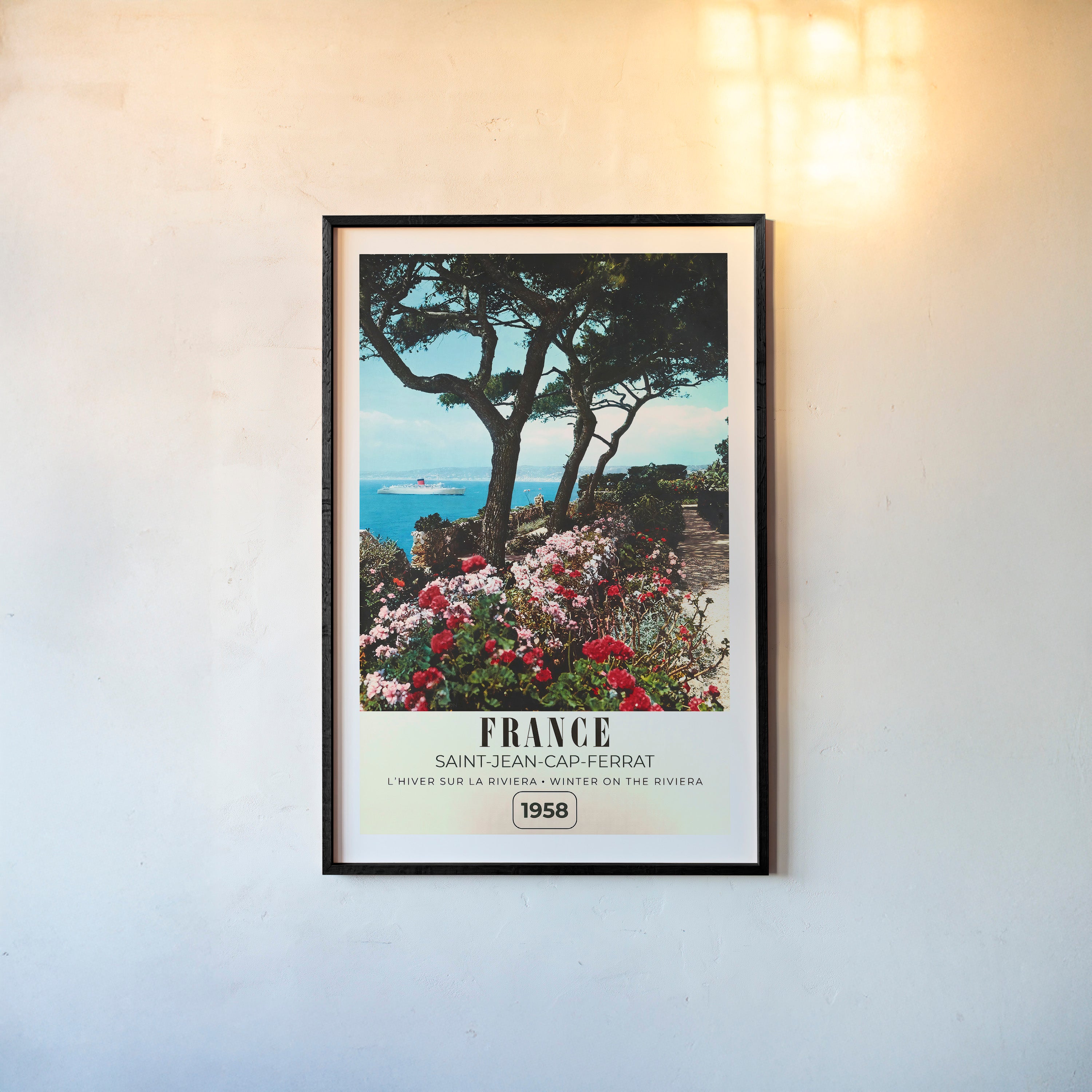 Framed poster of a river with flowers blooming around it and the text "France" in large letters, hanging on a wall with a light background