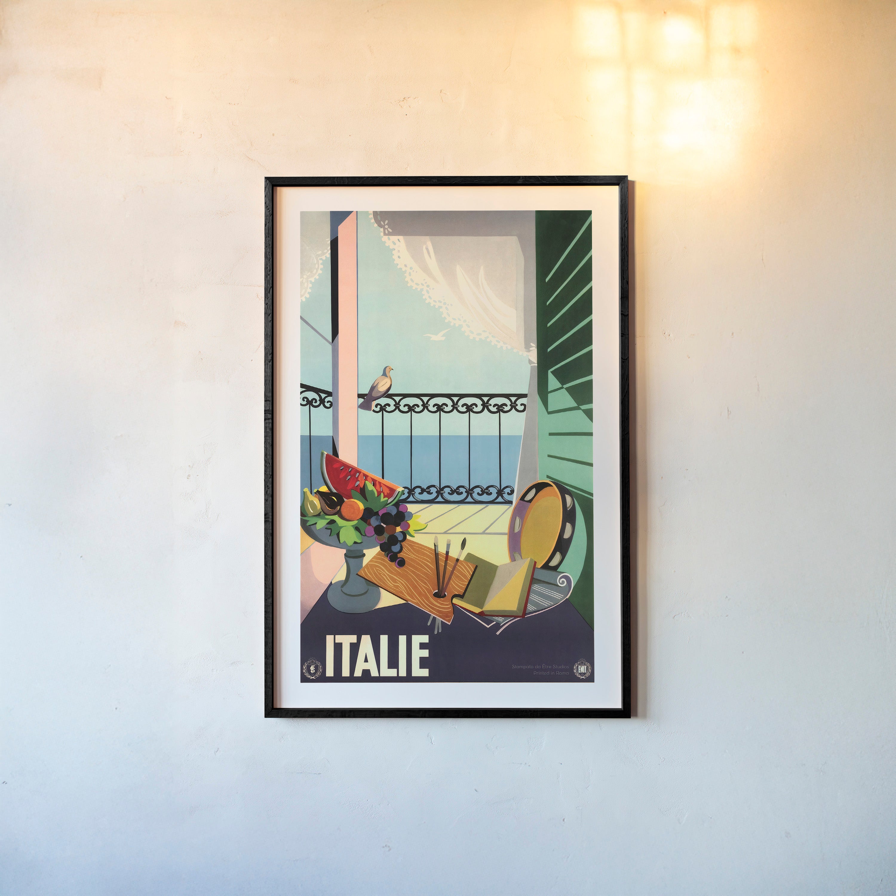 Framed poster of porch scene surrounded by artistic materials with the text "Italie" at the bottom hanging on a light background