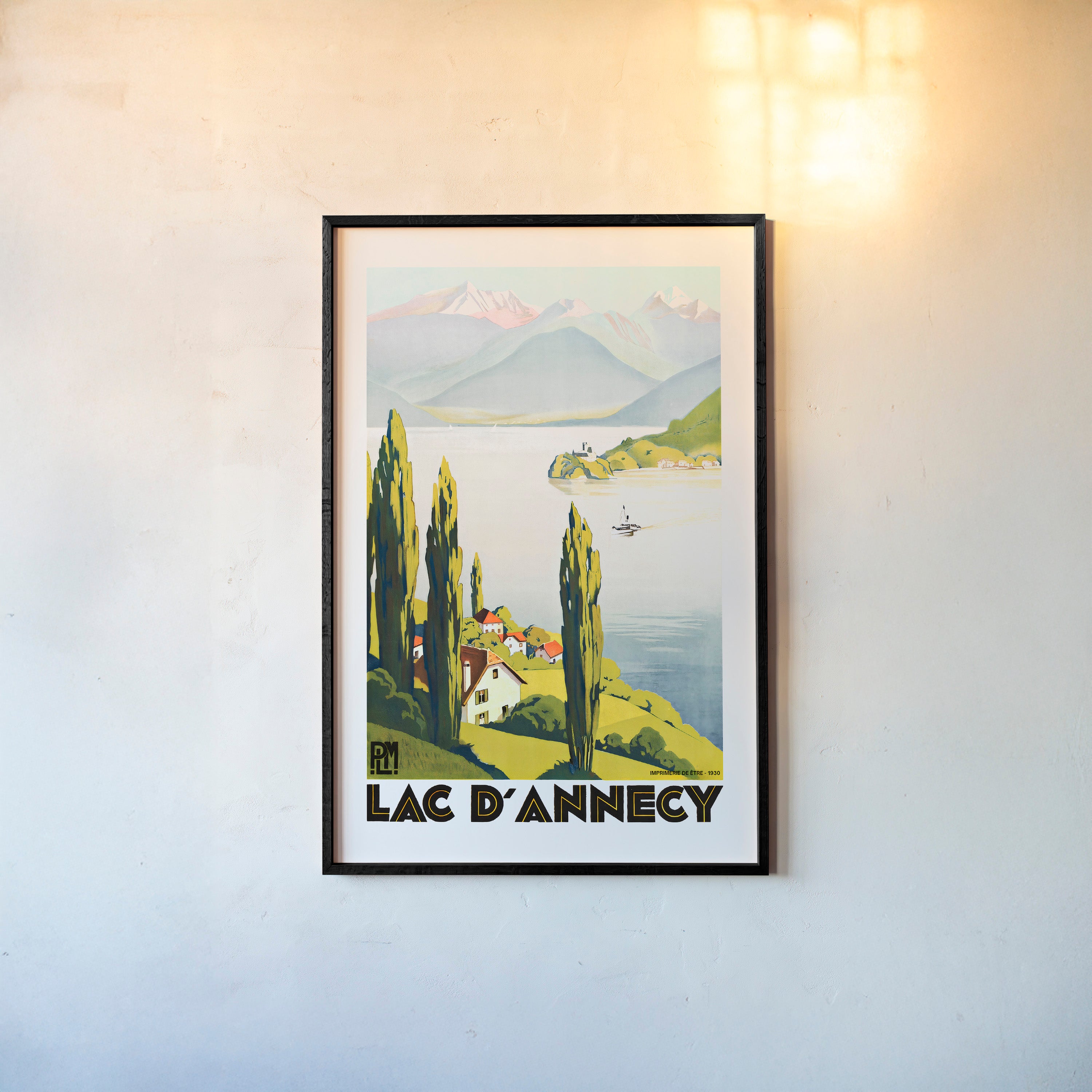Framed "Lac D'Annecy" poster featuring a lake with a scenic mountain background hanging on a light background