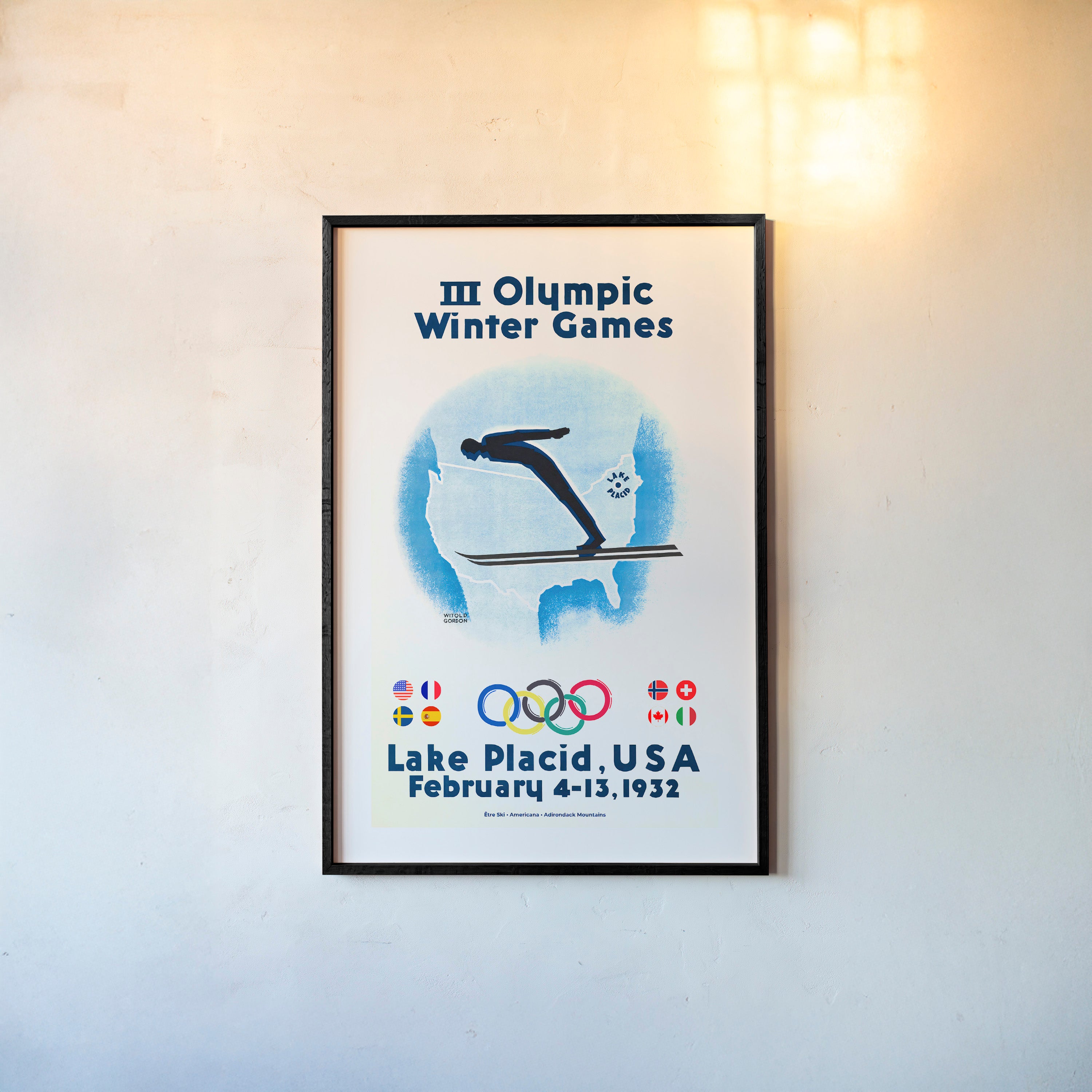 Framed poster of a skier with the United States map in the background and information on the 1932 Lake Placid winter olympic games hanging on a wall with a light background