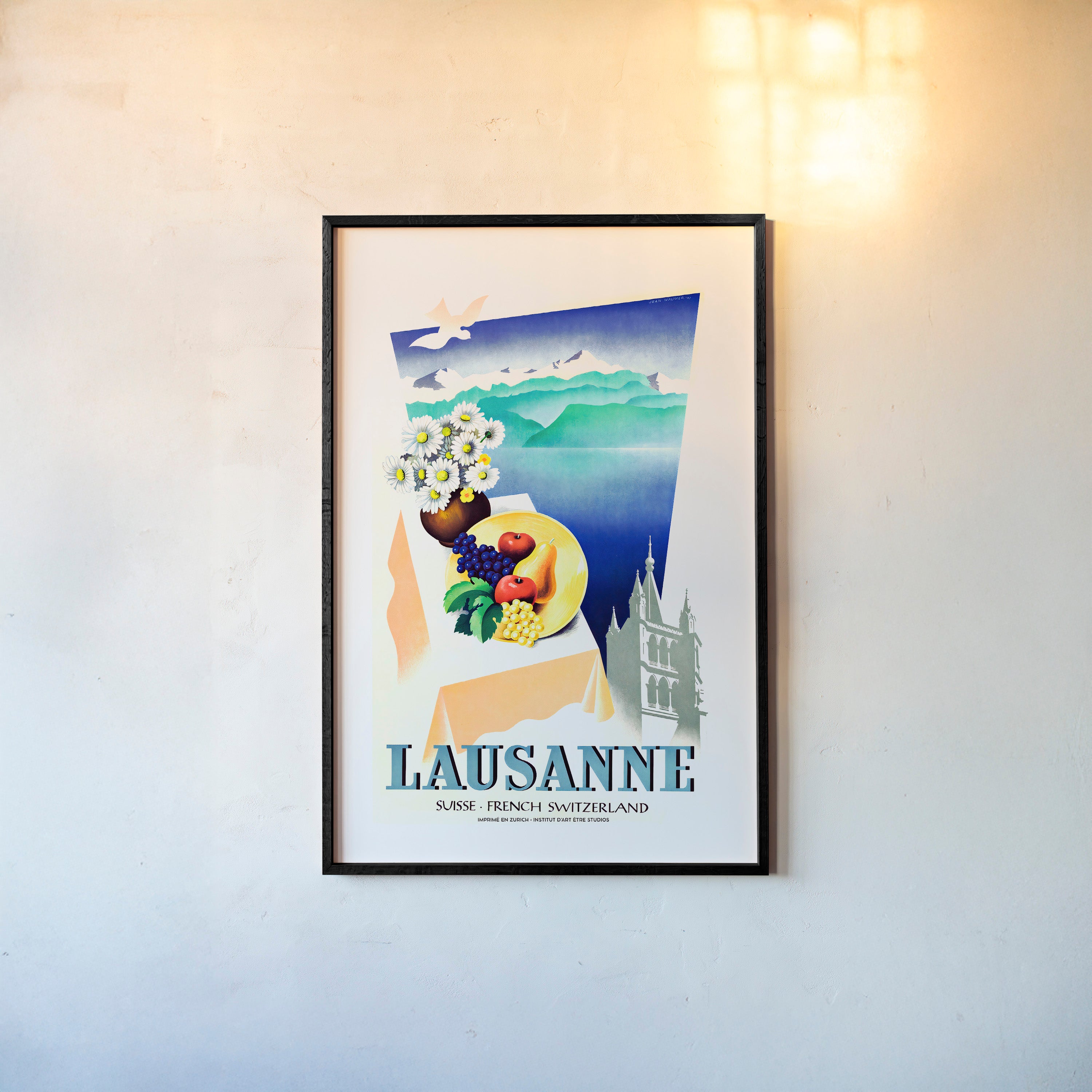 Framed poster of different elements with a mountain lake background and the text "Lausanne" at the bottom hanging on a light background