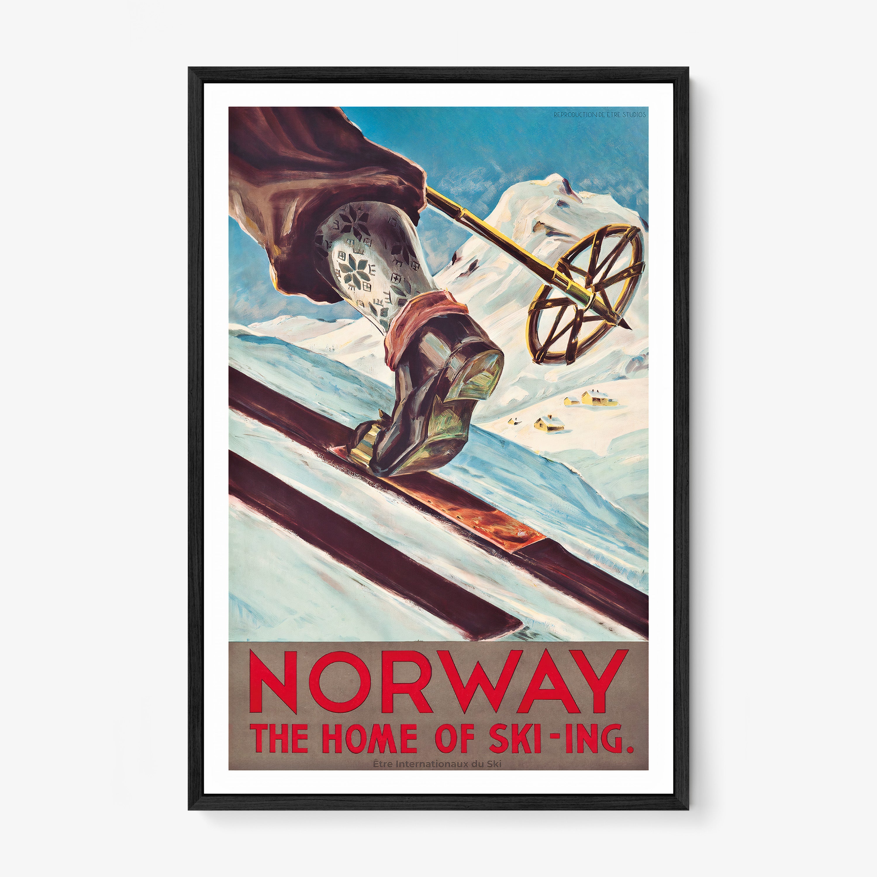 Framed poster featuring a close-up of a skier's leg and ski pole with patterned socks moving up a snowy hill with mountains in the background with the text "Norway, the home of ski-ing" at the bottom hanging on a white background