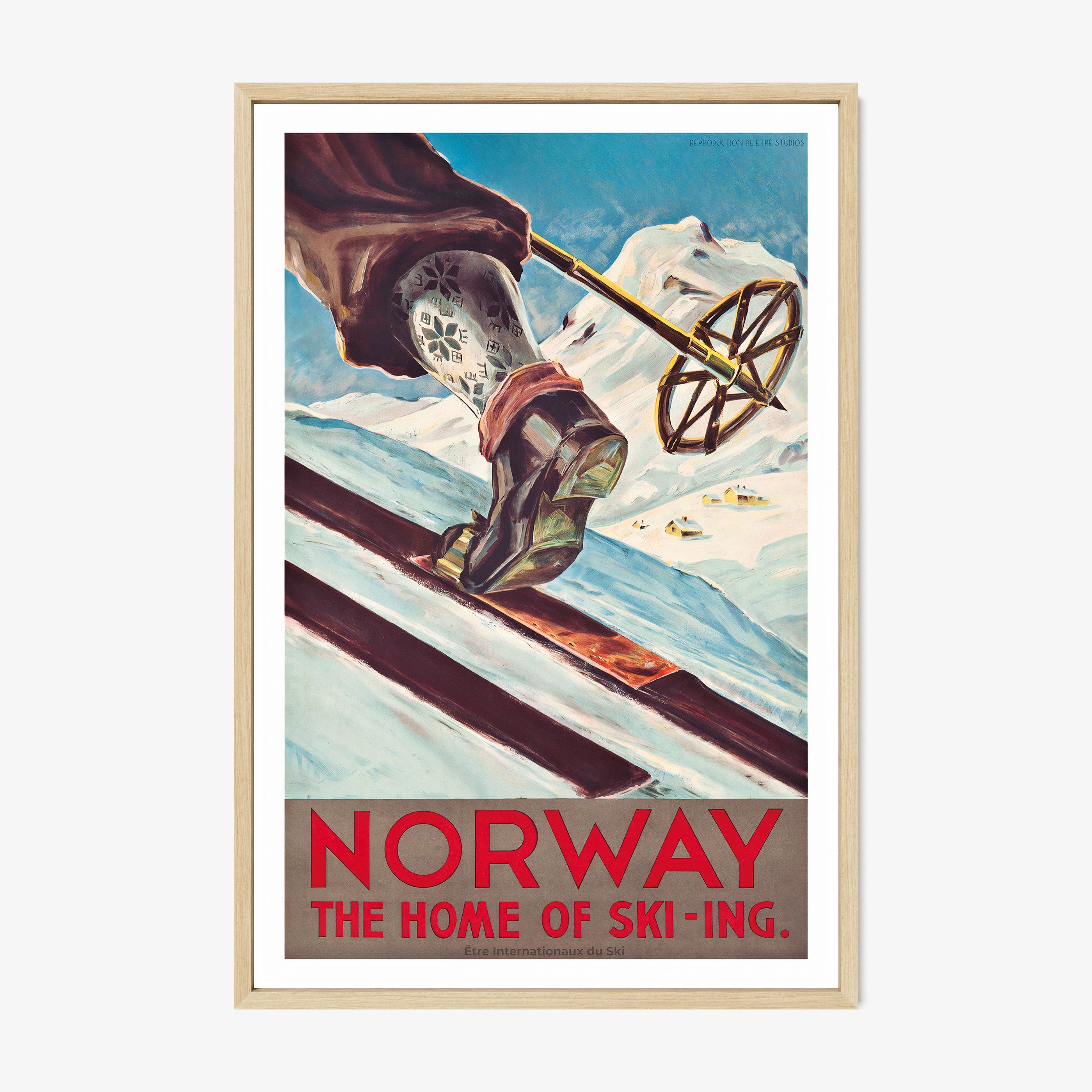 Framed poster featuring a close-up of a skier's leg and ski pole with patterned socks moving up a snowy hill with mountains in the background with the text "Norway, the home of ski-ing" at the bottom hanging on a white background