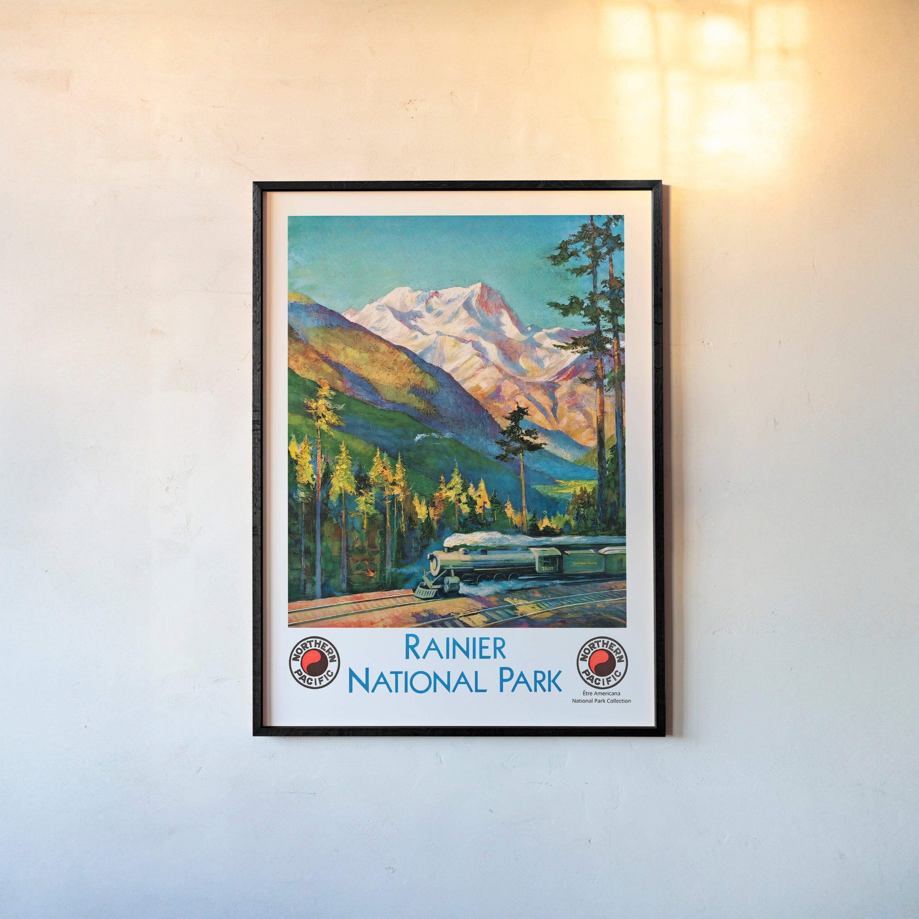 Framed "Rainier National Park" poster featuring a train and mountain scene hanging on a light background