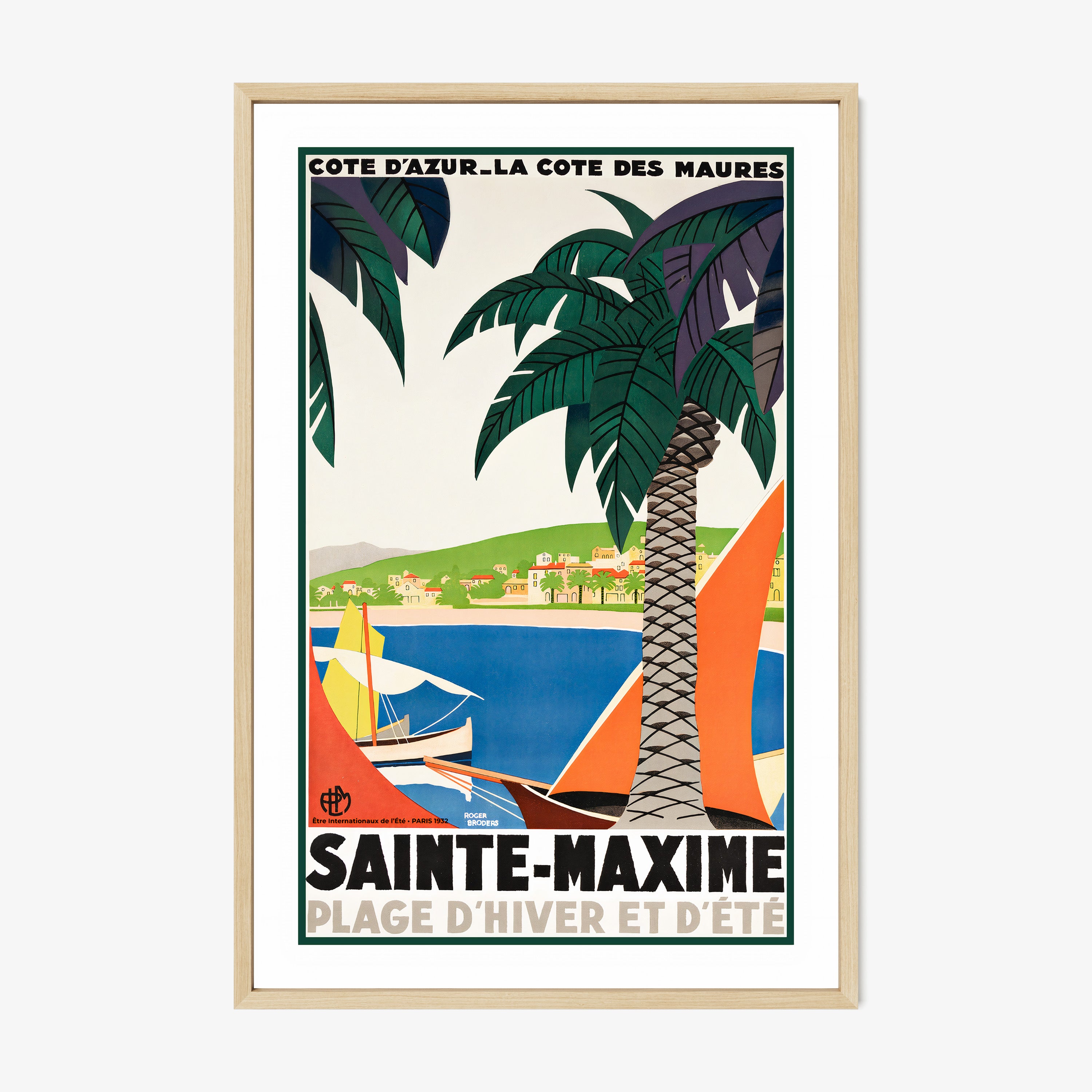 Framed poster featuring sailboats on a blue sea surrounded by palm trees and a coastal village with the text "Sainte-Maxime" at the bottom hanging on a white background
