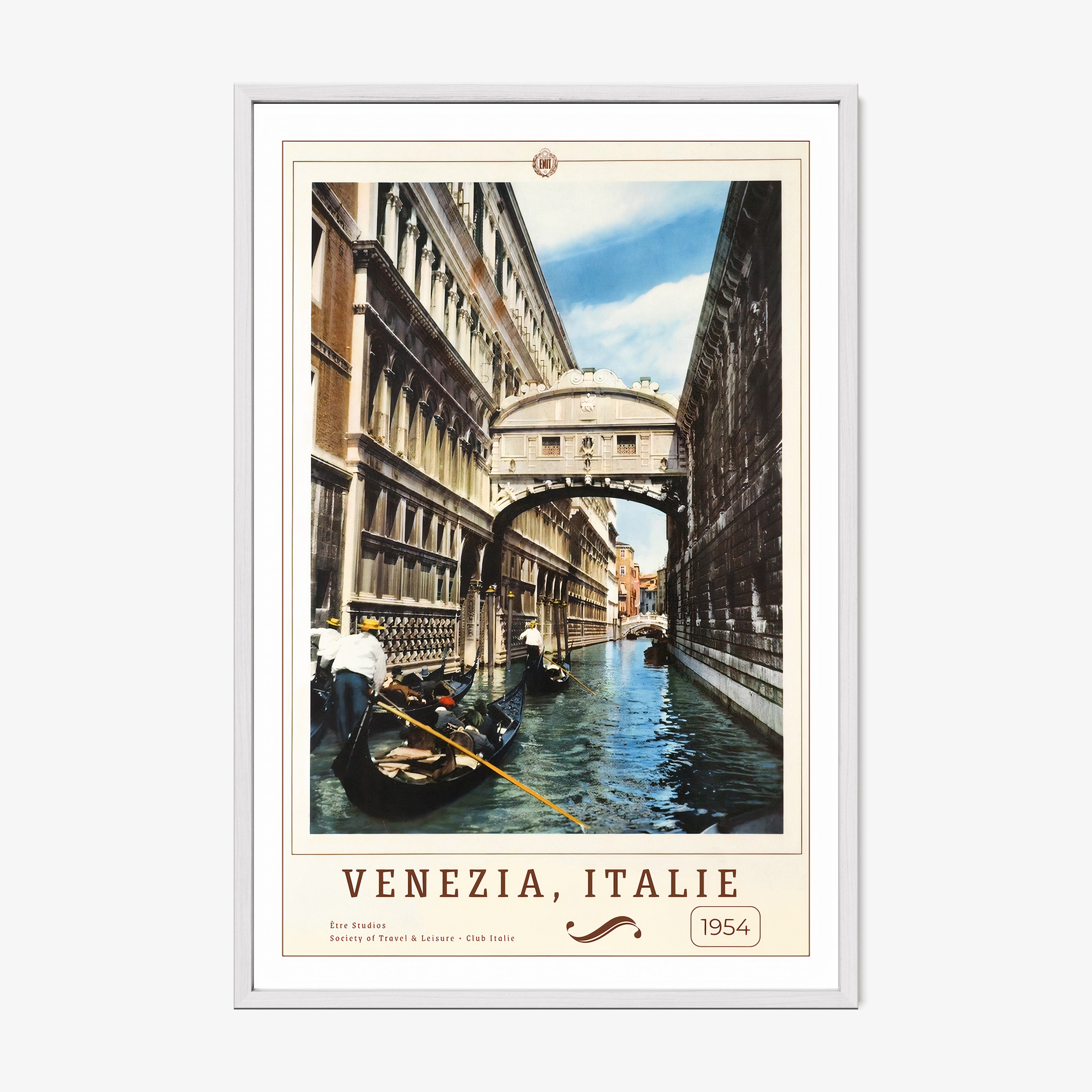 Framed poster of people on boats in a canal in between buildings with the text "Venezia, Italie" in large hanging on a wall with a light background