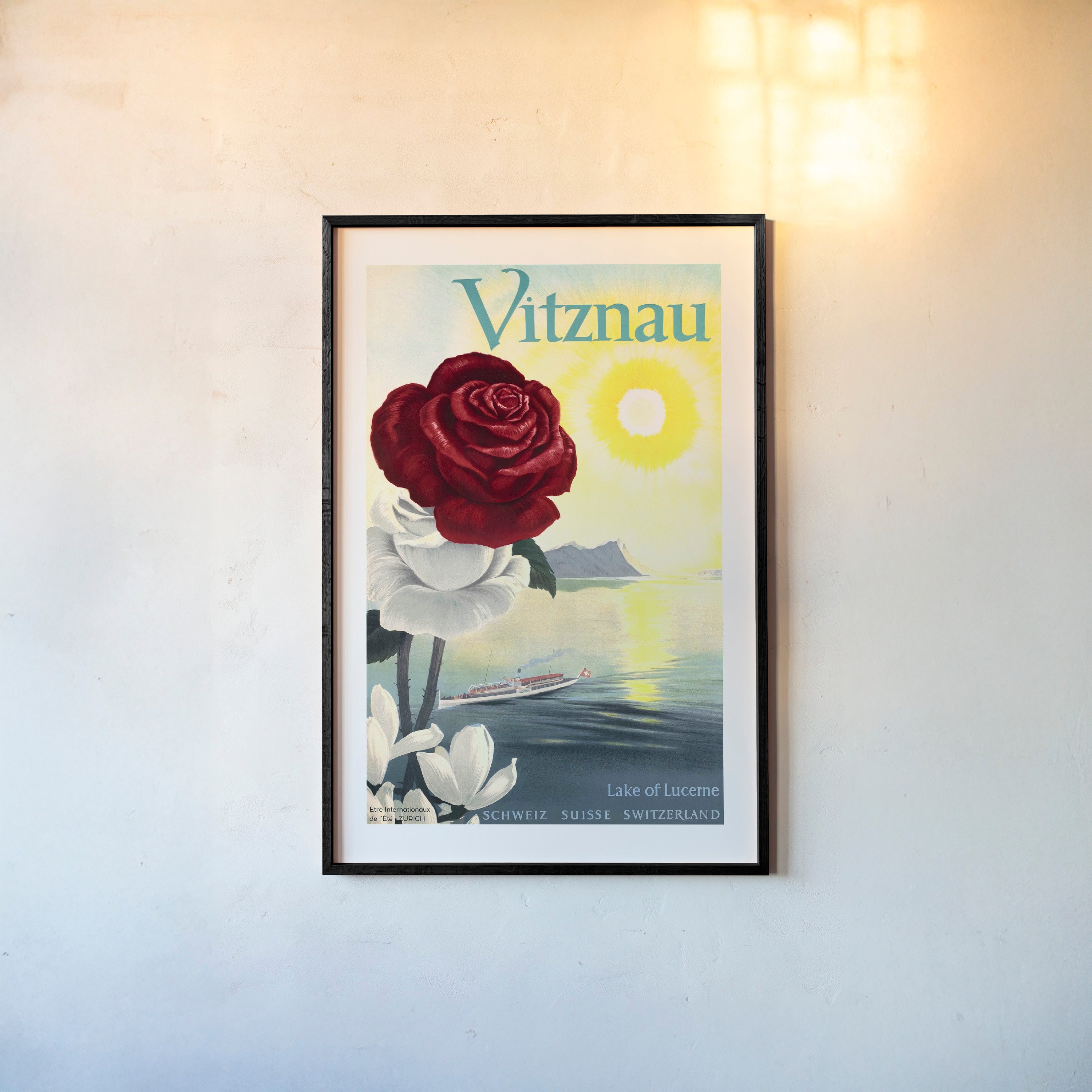 Framed poster of a large rose and an ocean background with the text "Vitznau" at the top hanging on a wall with a light background