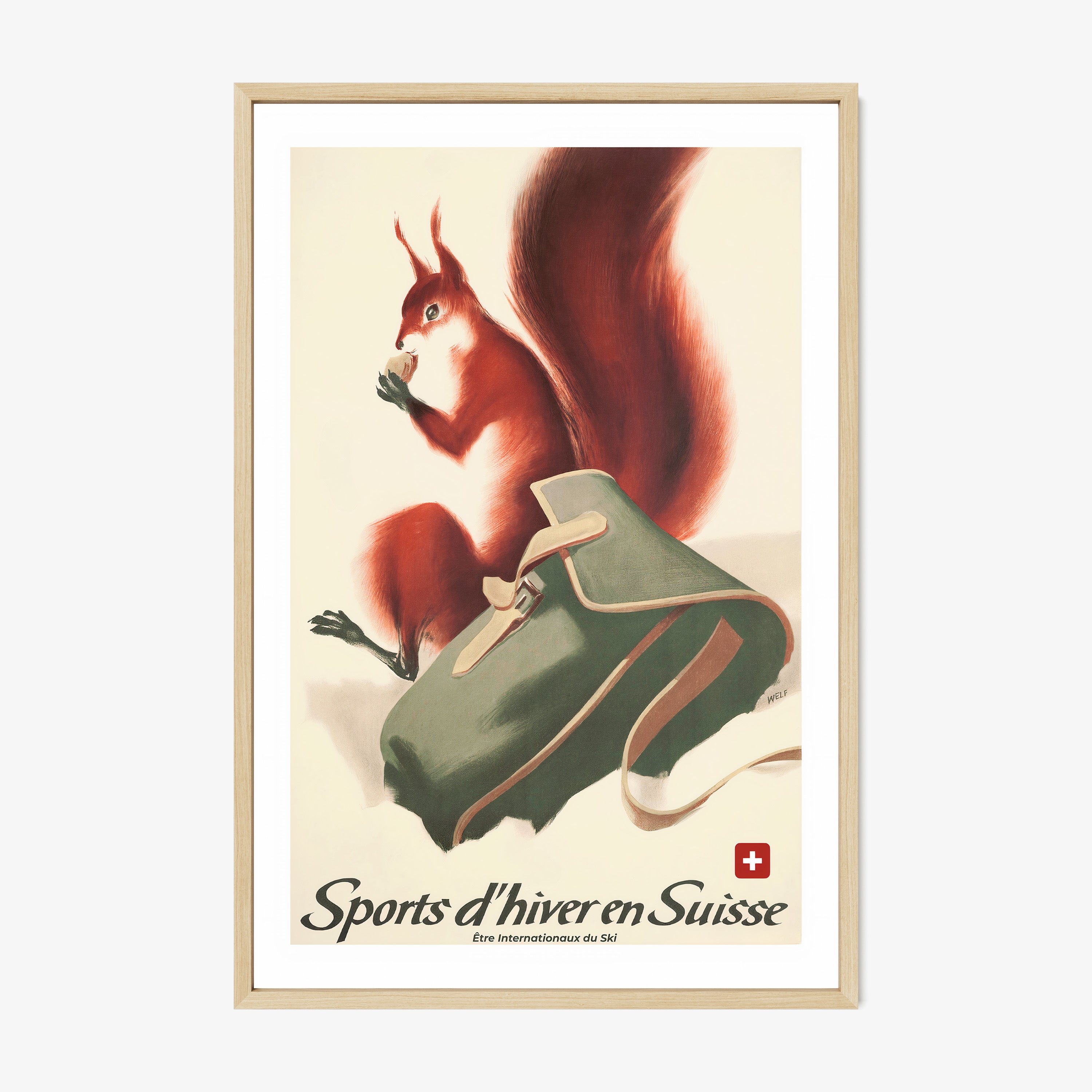 Framed poster of a fox next to a backpack in the snow with the text "Sports d'hiver en Suisse" at the bottom hanging on a wall with a light backdrop