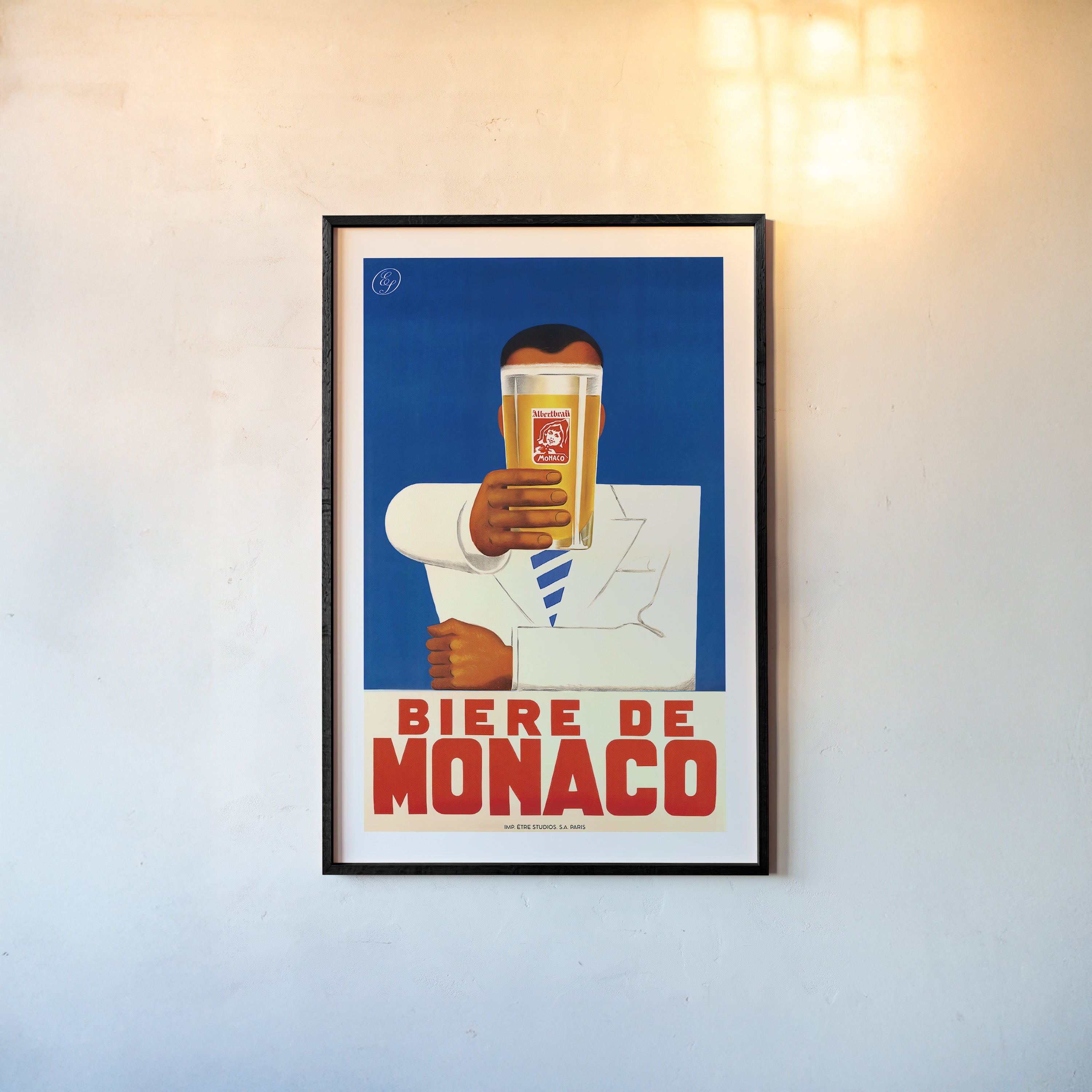A framed poster features a person holding a beer with bold text "Biere De Monaco"