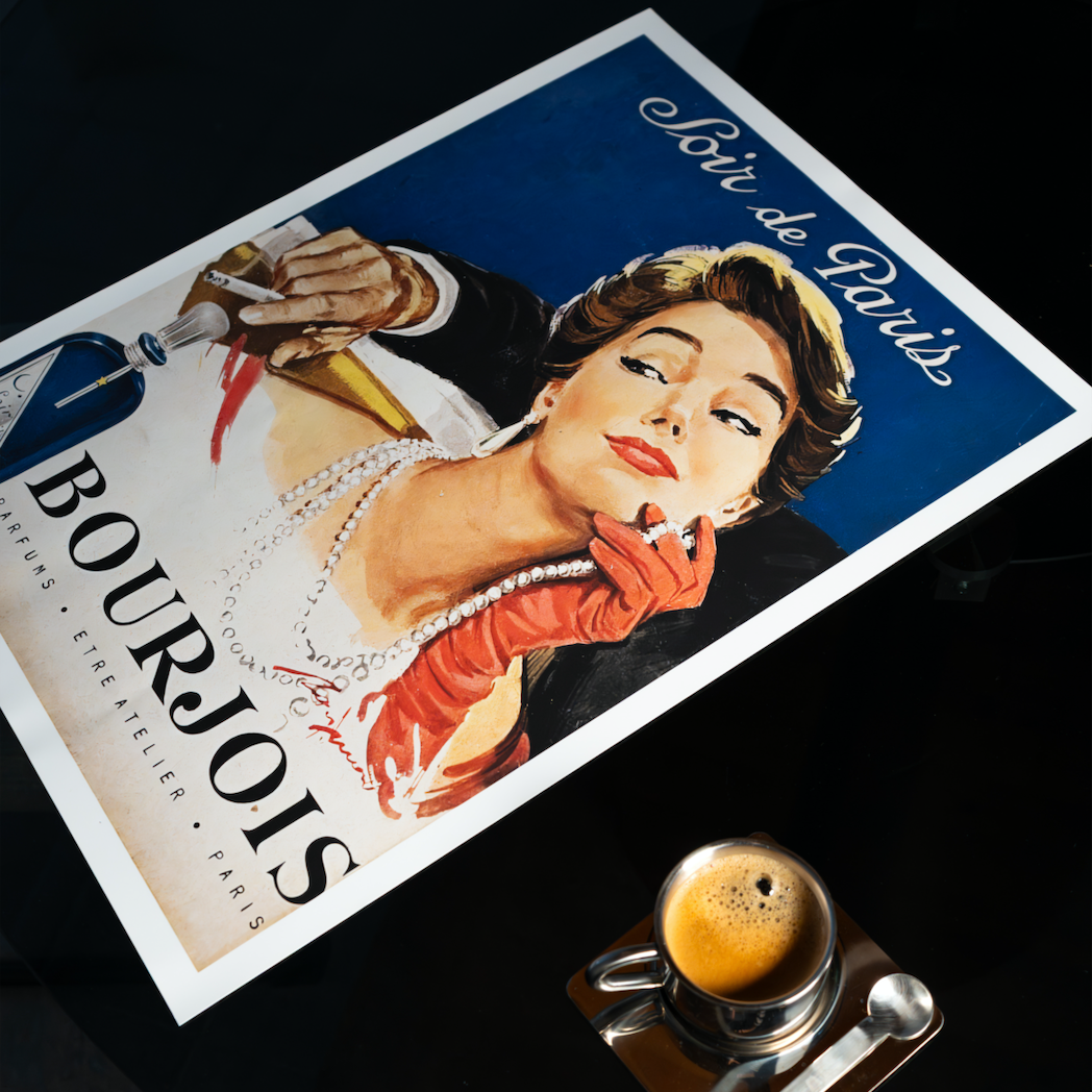 Vintage Bourjois advertisement poster on a dark surface with a small round object in the foreground.