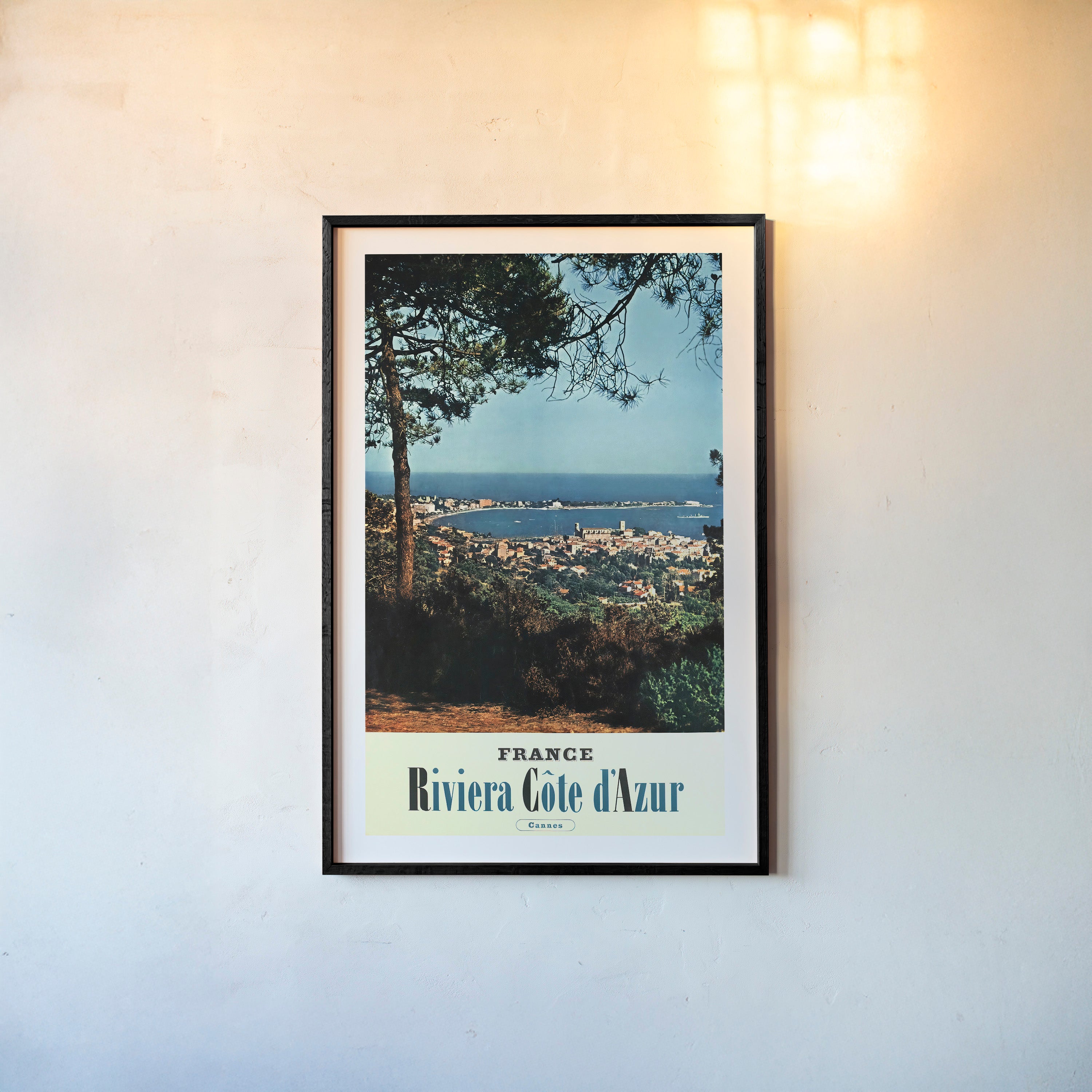 Poster of an ocean and city viewpoint with the text "France Riviera Cote d'Azur" on the bottom hanging on a light background