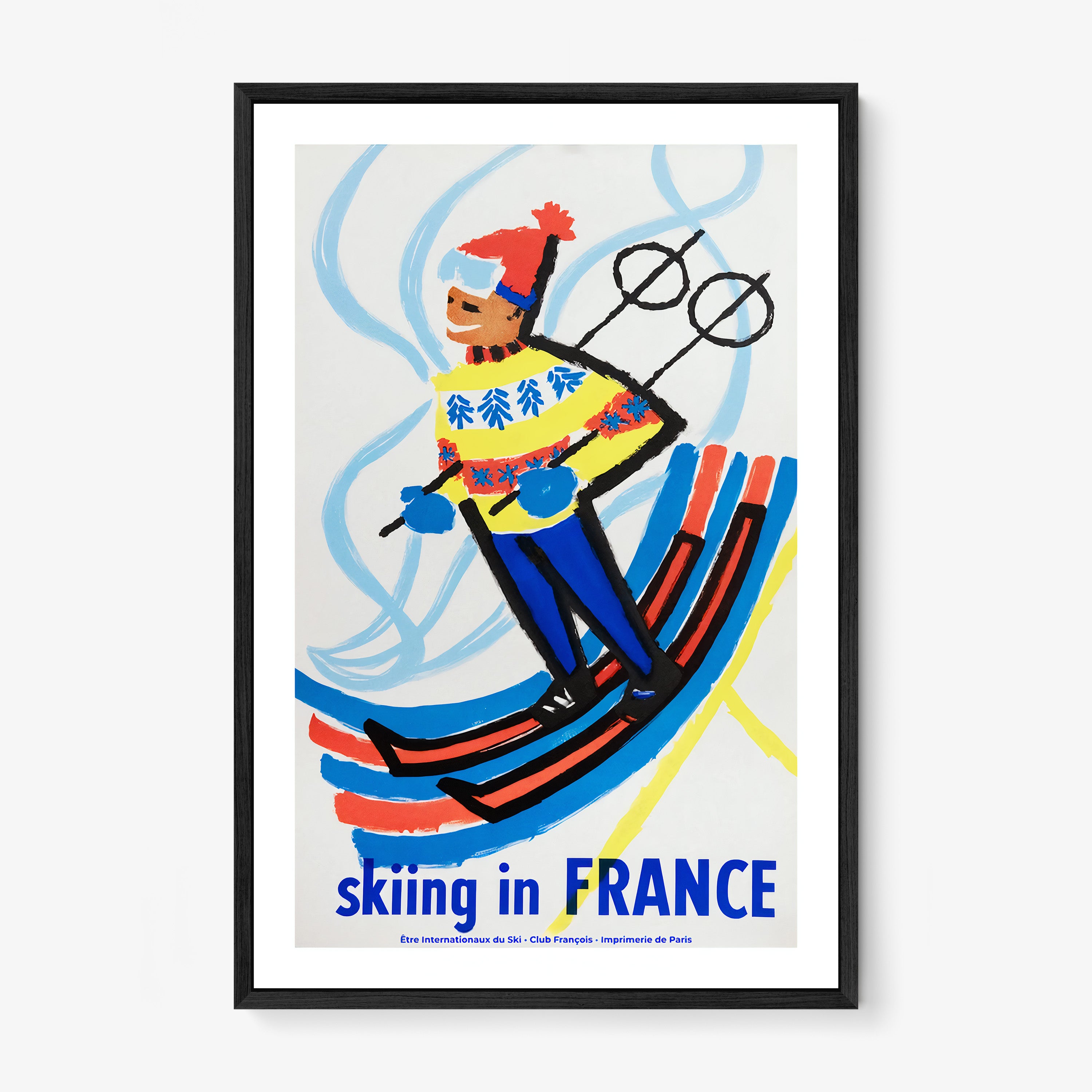 Framed poster of a skier with 'Skiing in France' text on a wall.