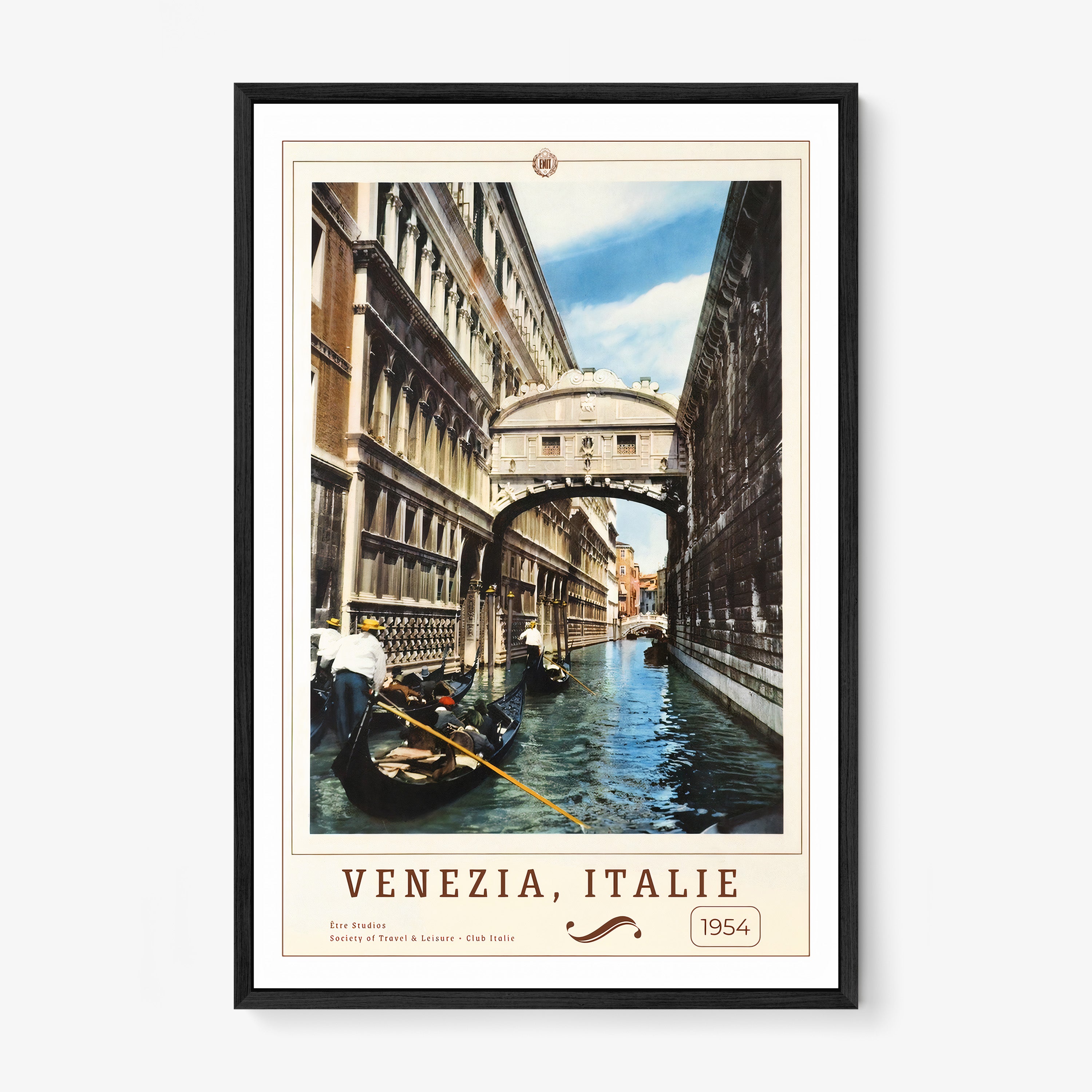 Framed poster of people on boats in a canal in between buildings with the text "Venezia, Italie" in large hanging on a wall with a light background 